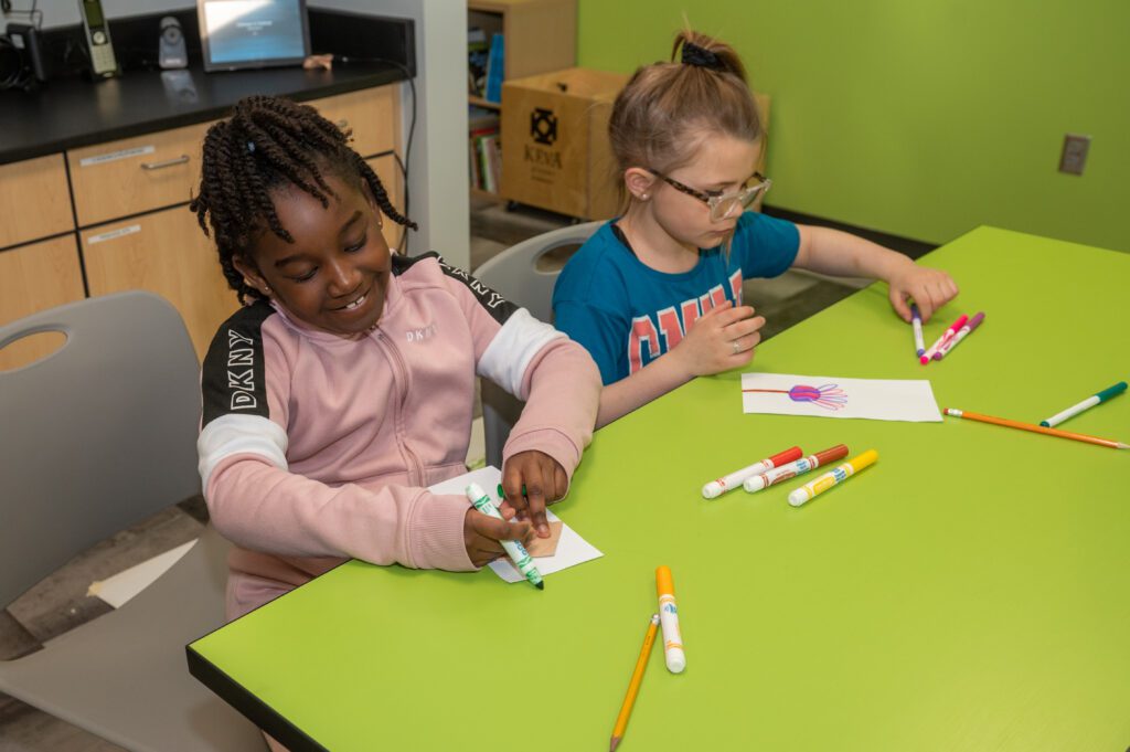 picture of two children drawing with markers