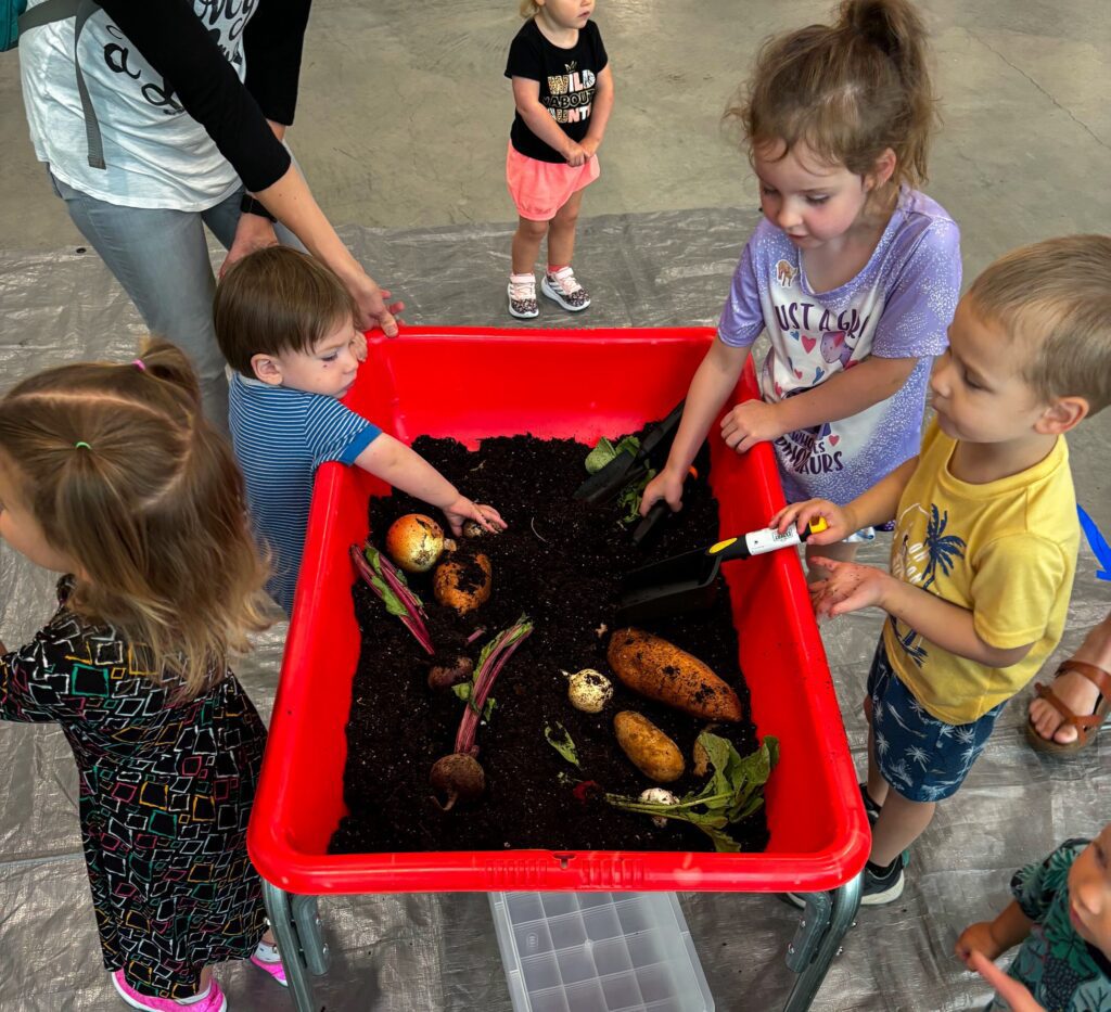 picture of kids playing with vegetables in the soil